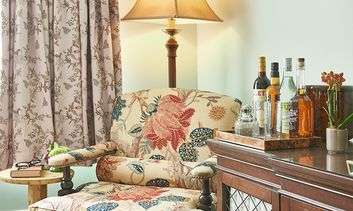 Floral-patterned chair and liquor bottles at our New Orleans hotel near Tulane