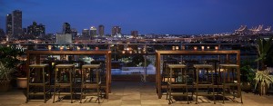 Outdoor tall tables with stools looking out to New Orleans at night from The Pontchartrain rooftop