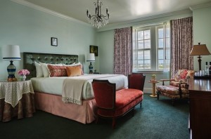 Side view of the large hotel king bed with floral curtains & city views of New Orleans