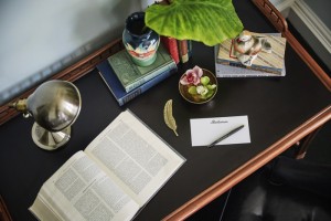 Looking down at our Pontchartrain desk with a book, lamp and green plant at our historic hotel in New Orleans