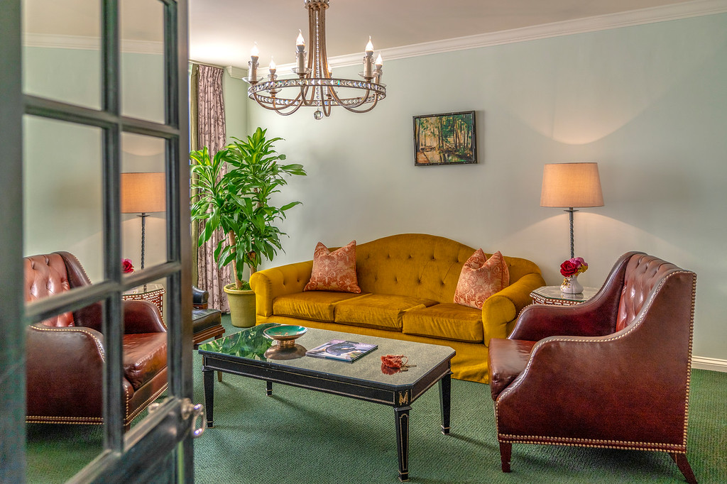 View of a separate seating area with gold couch and leather chairs at our New Orleans accommodations