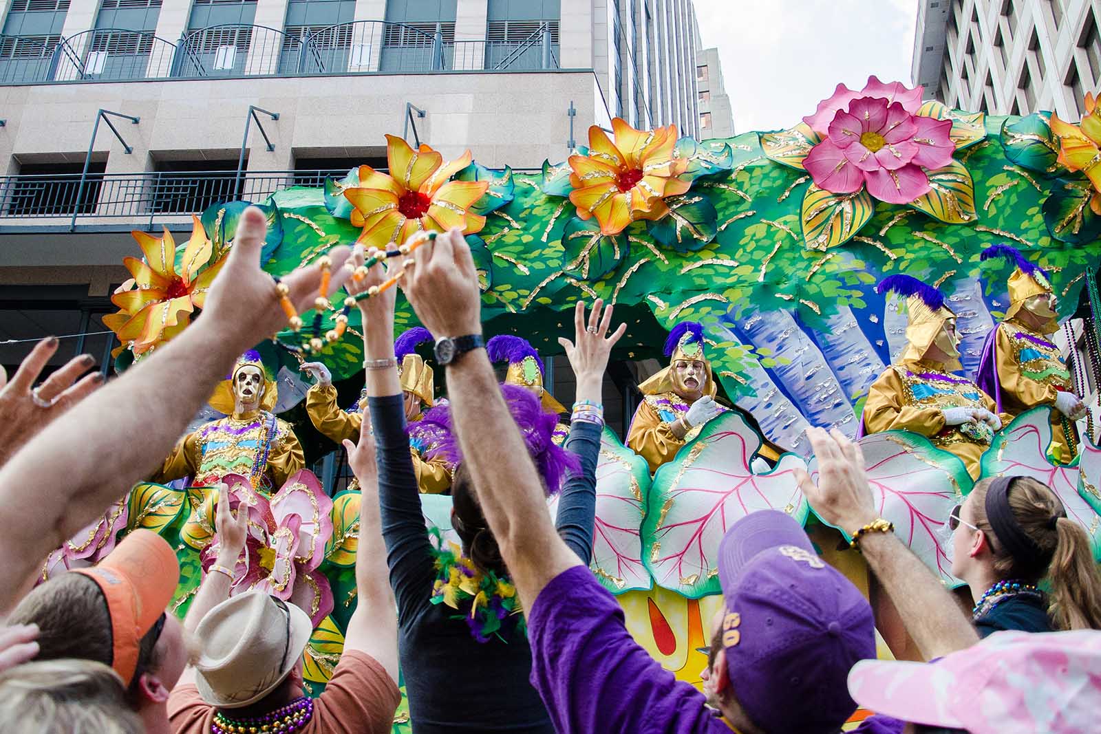 Mardi Gras float with bright colored flowers and visitors reaching out near our Garden District hotel